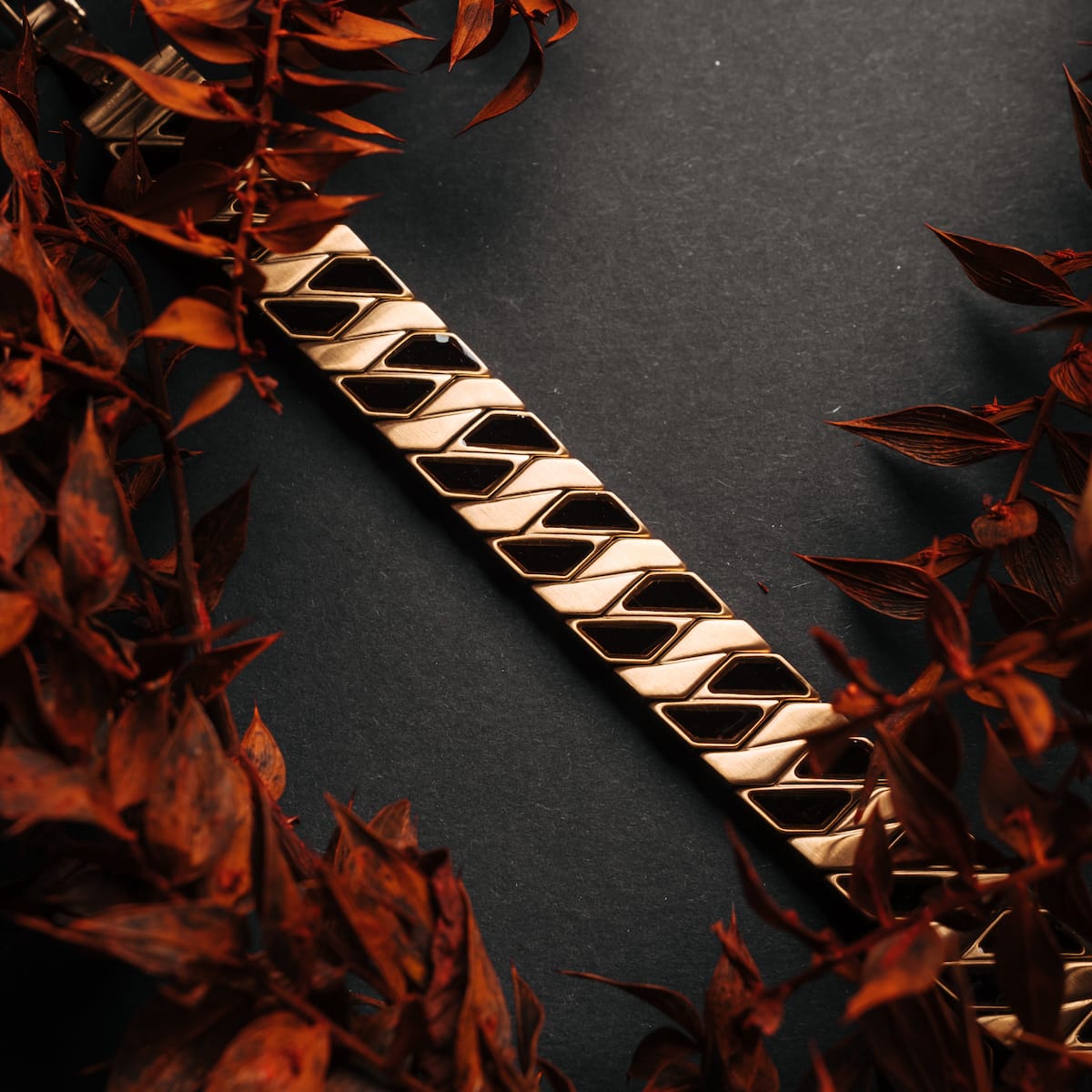 "Baritone", a stylish bracelet in maple and gold tones with a geometric pattern, surrounded by autumn leaves.