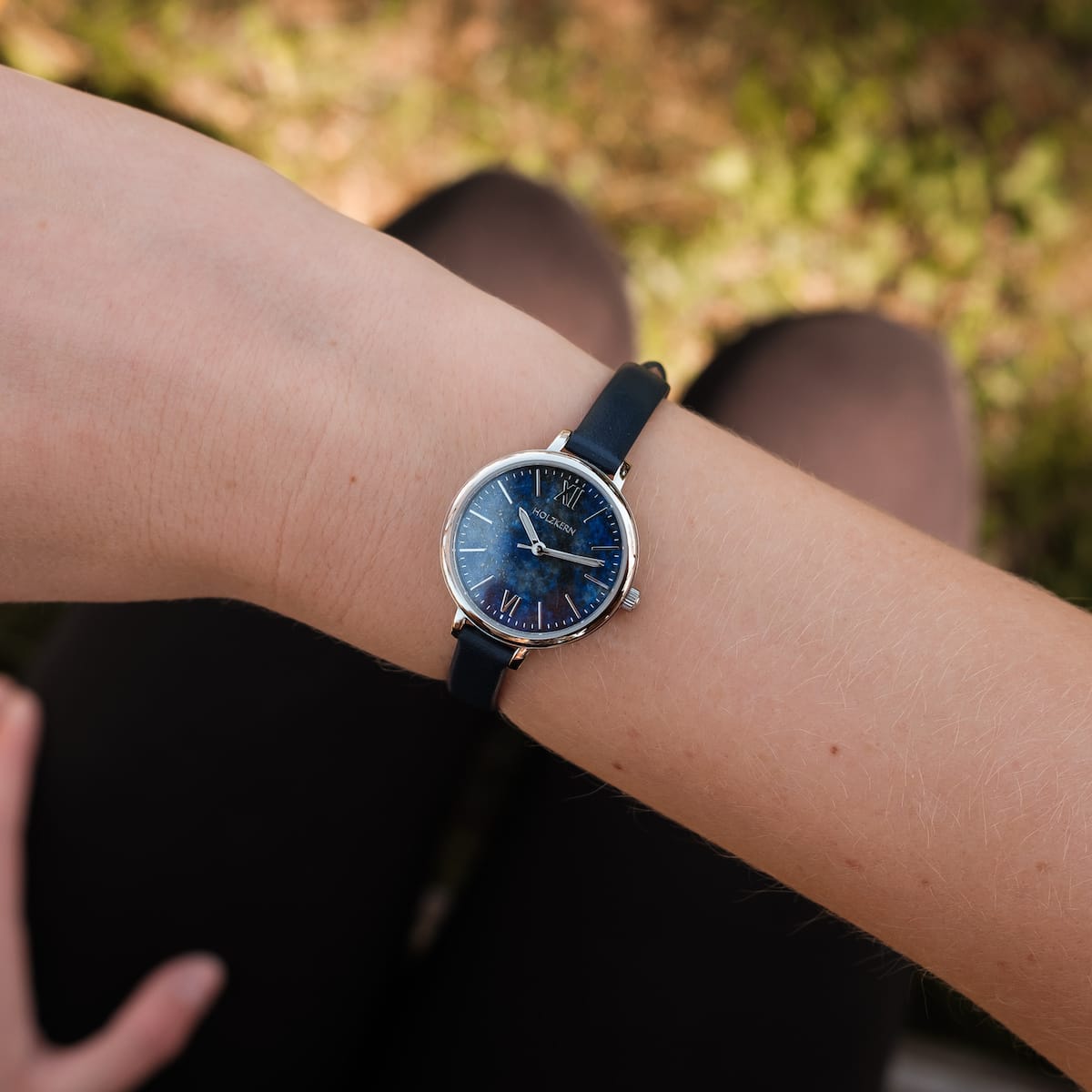 "Teresa" watch featuring lapis lazuli dial and silver accents on wrist outdoors.