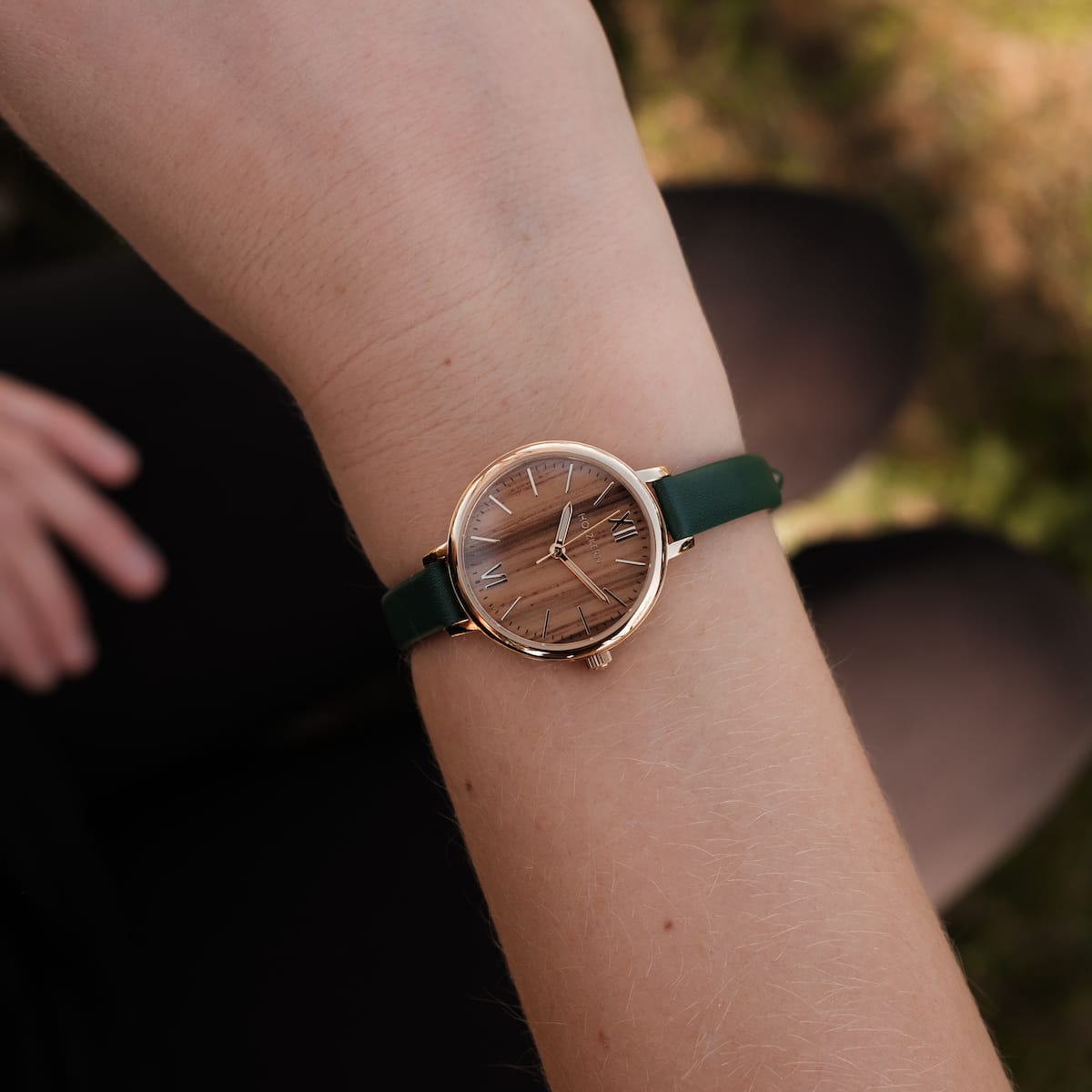 "Wangari" wristwatch featuring a Zebrawood dial and gold accents with a green strap for an elegant, natural look.