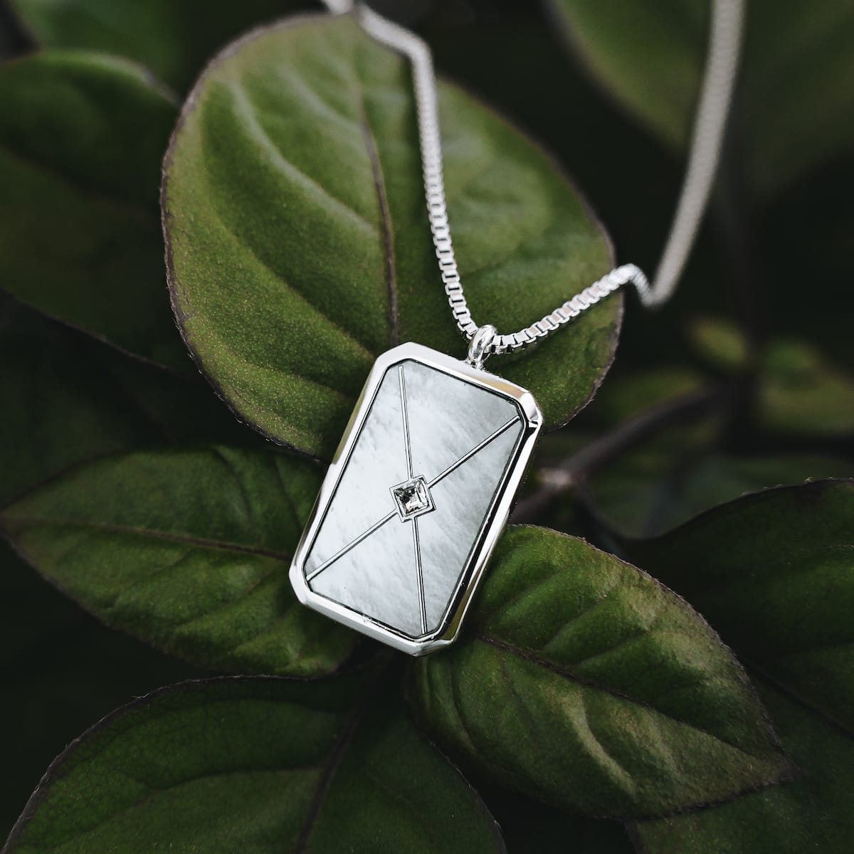 "Aquarell Necklace" necklace features a geometric silver design with white nacre accents, offering an elegant and modern aesthetic.