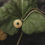 Stencil Necklace: A stylish marble and gold necklace with a radiant design on a leafy background.