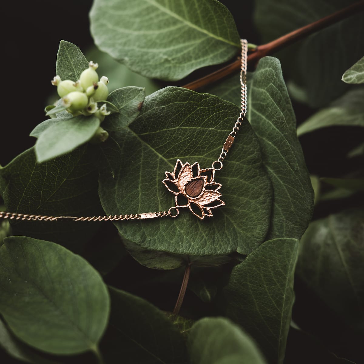 "Balance Bracelet" bracelet featuring a walnut and rose gold design atop vibrant green leaves.