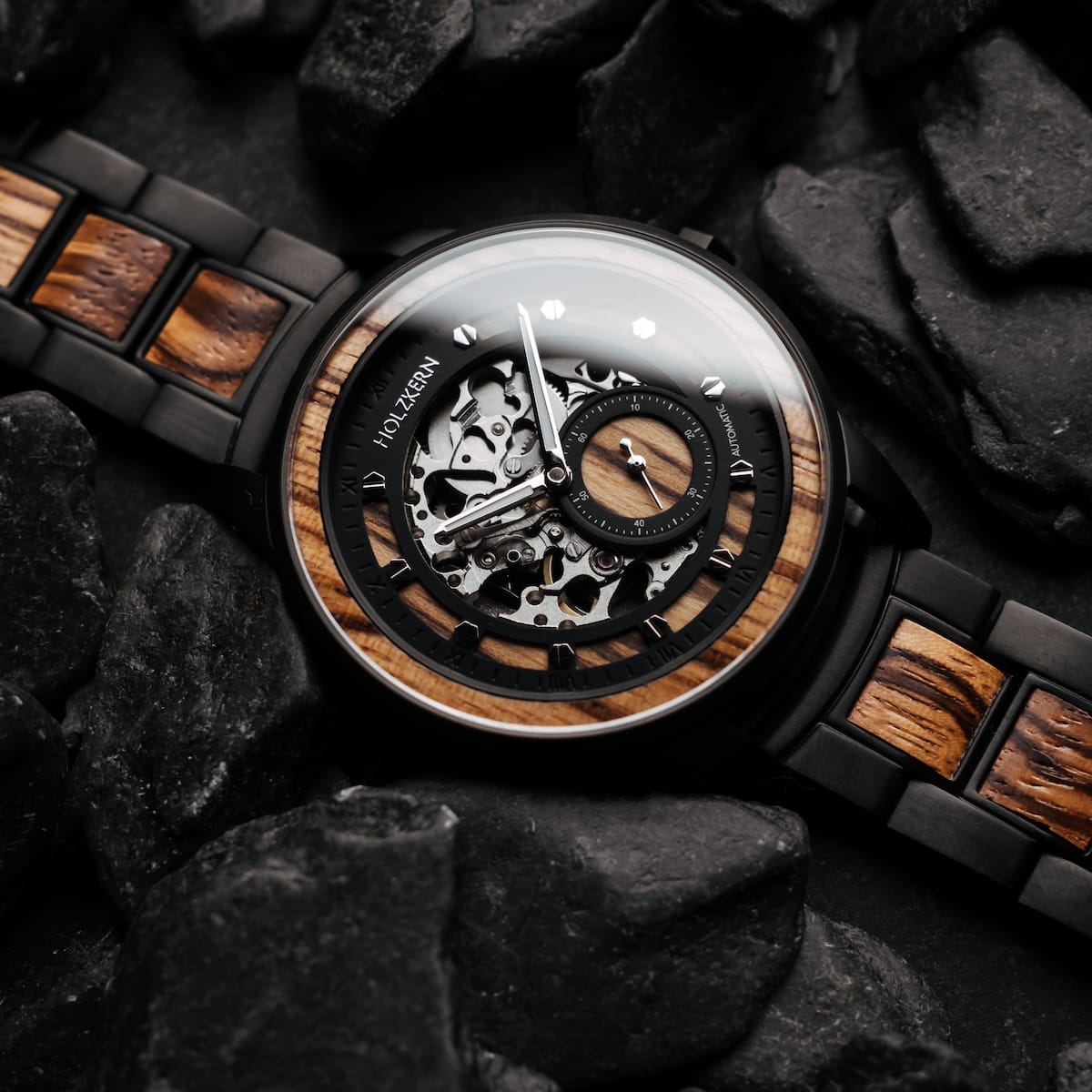 "Sternum" watch features a striking zebrawood and black design with exposed mechanics, set against dark stone.