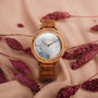 "Capri" watch with olive wood and nacre accents, styled elegantly with a natural backdrop.