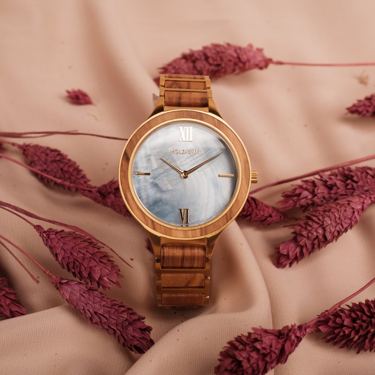 "Capri" watch with olive wood and nacre accents, styled elegantly with a natural backdrop.