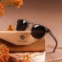 "The Trustworthy" sunglasses, featuring a sleek design with Leadwood and Ash elements, set against a warm, earthy background.