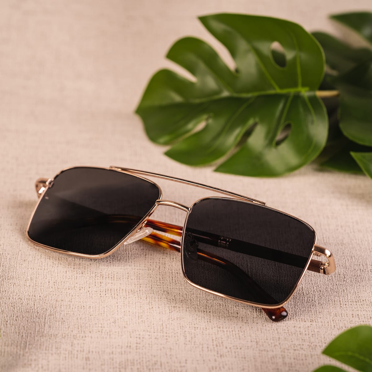 "The Talisman" sunglasses feature a sleek walnut and matte gold design with a modern aesthetic.