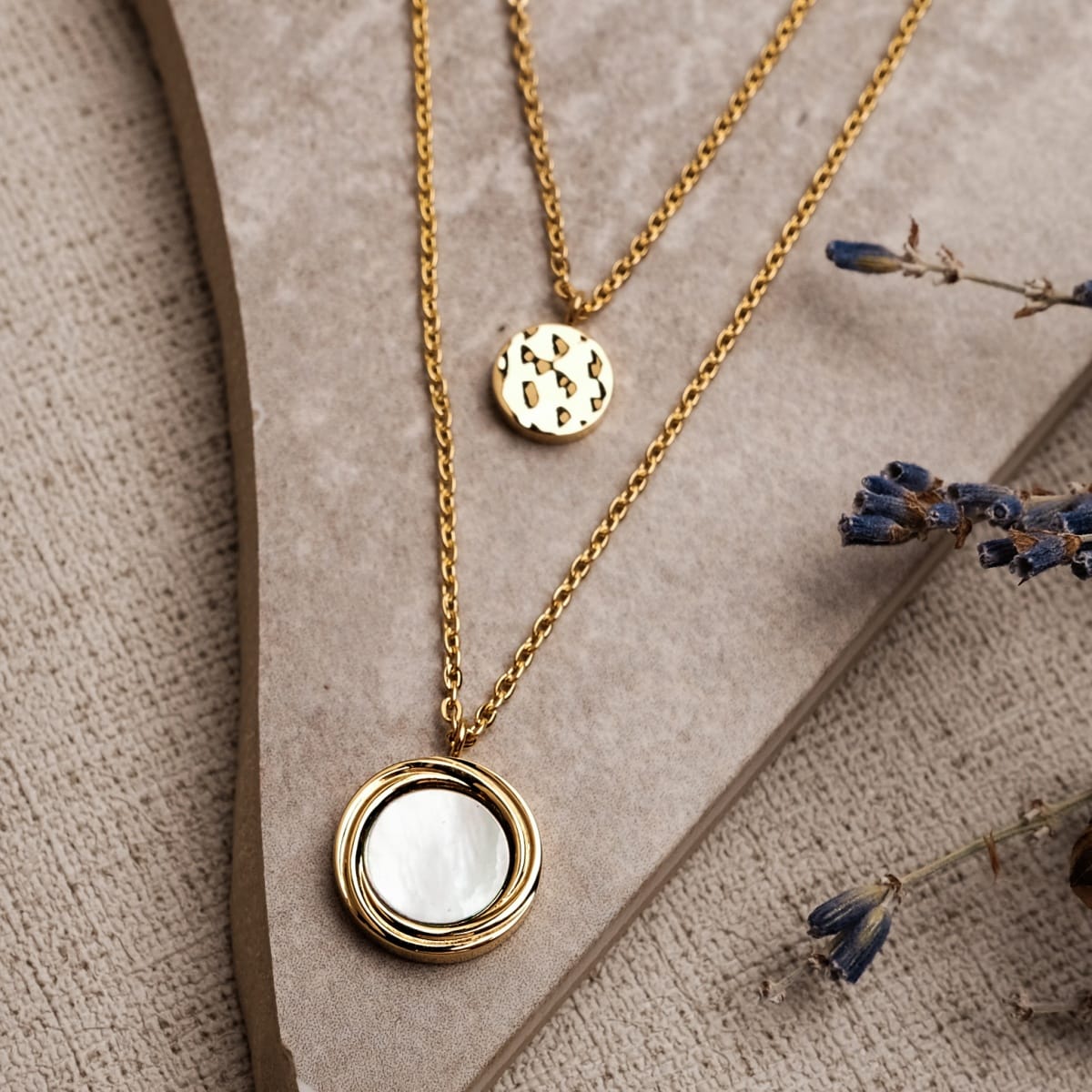 "Zendala Necklace", a double-layered gold necklace with a white nacre pendant, offering an elegant and sophisticated style.