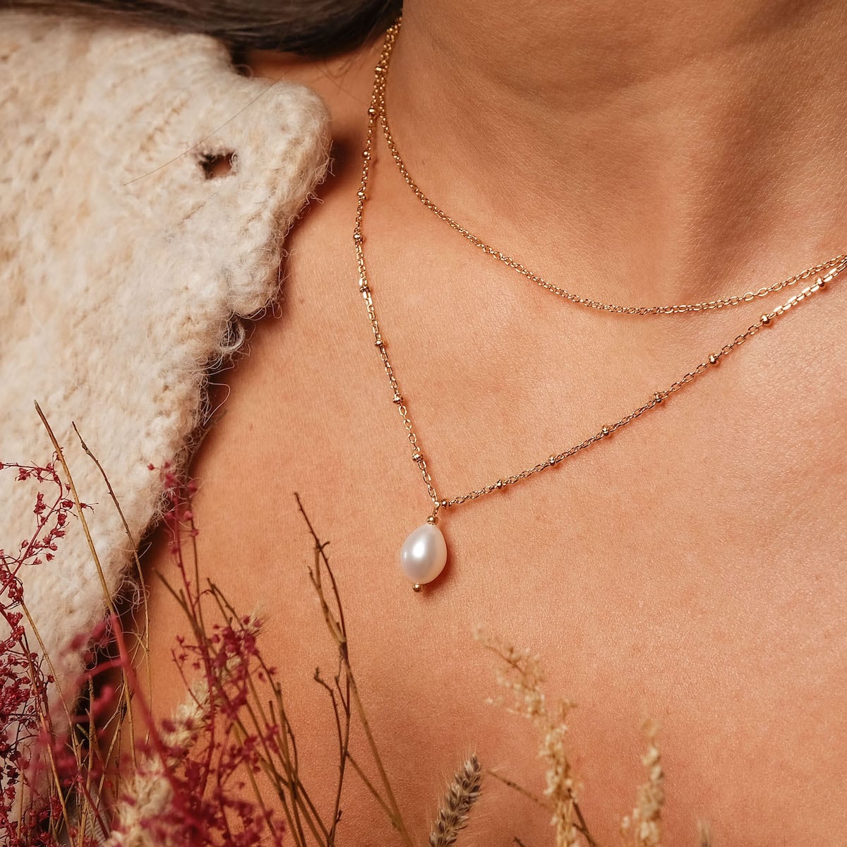 "Panoramic Necklace" necklace featuring a gold chain with a white pearl pendant, styled elegantly on a neckline.