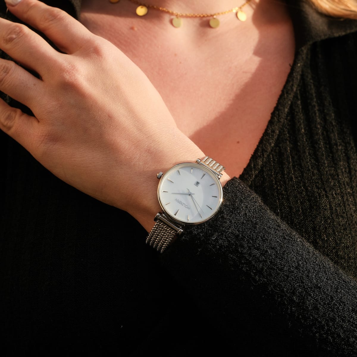 Piccolo elegant watch, nacre face with silver accents and mesh band, worn on wrist.