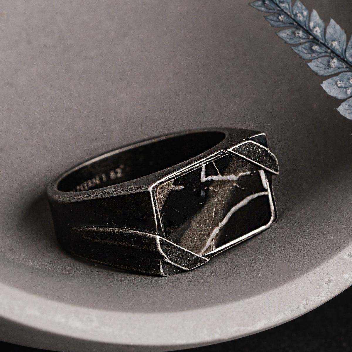 "Binomial Ring" ring featuring a marble and antique silver style in a modern, angular design.