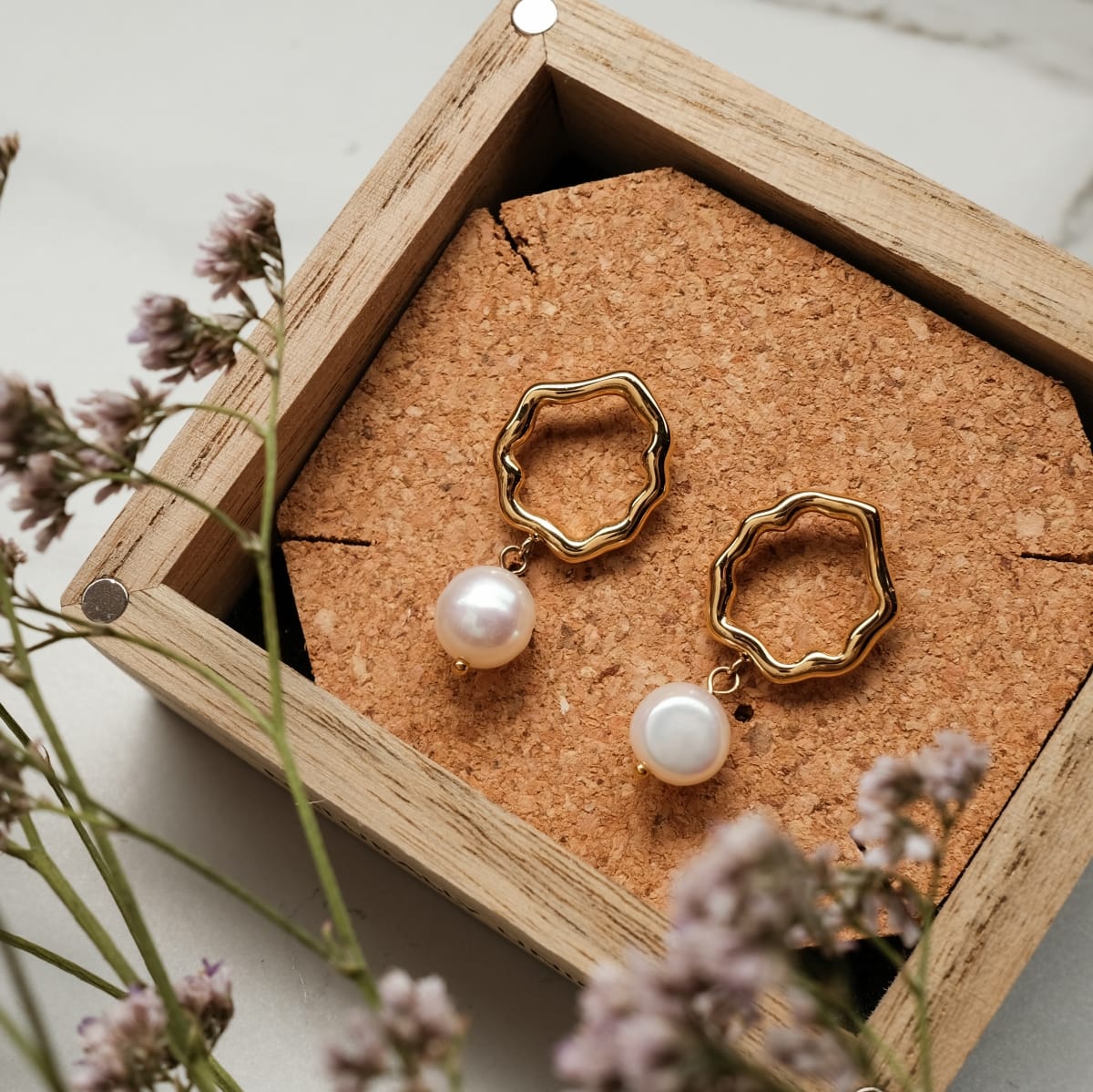 "Oceanfoam Earrings" elegant earrings in pearl and gold, featuring a wavy design in a stylish presentation box.