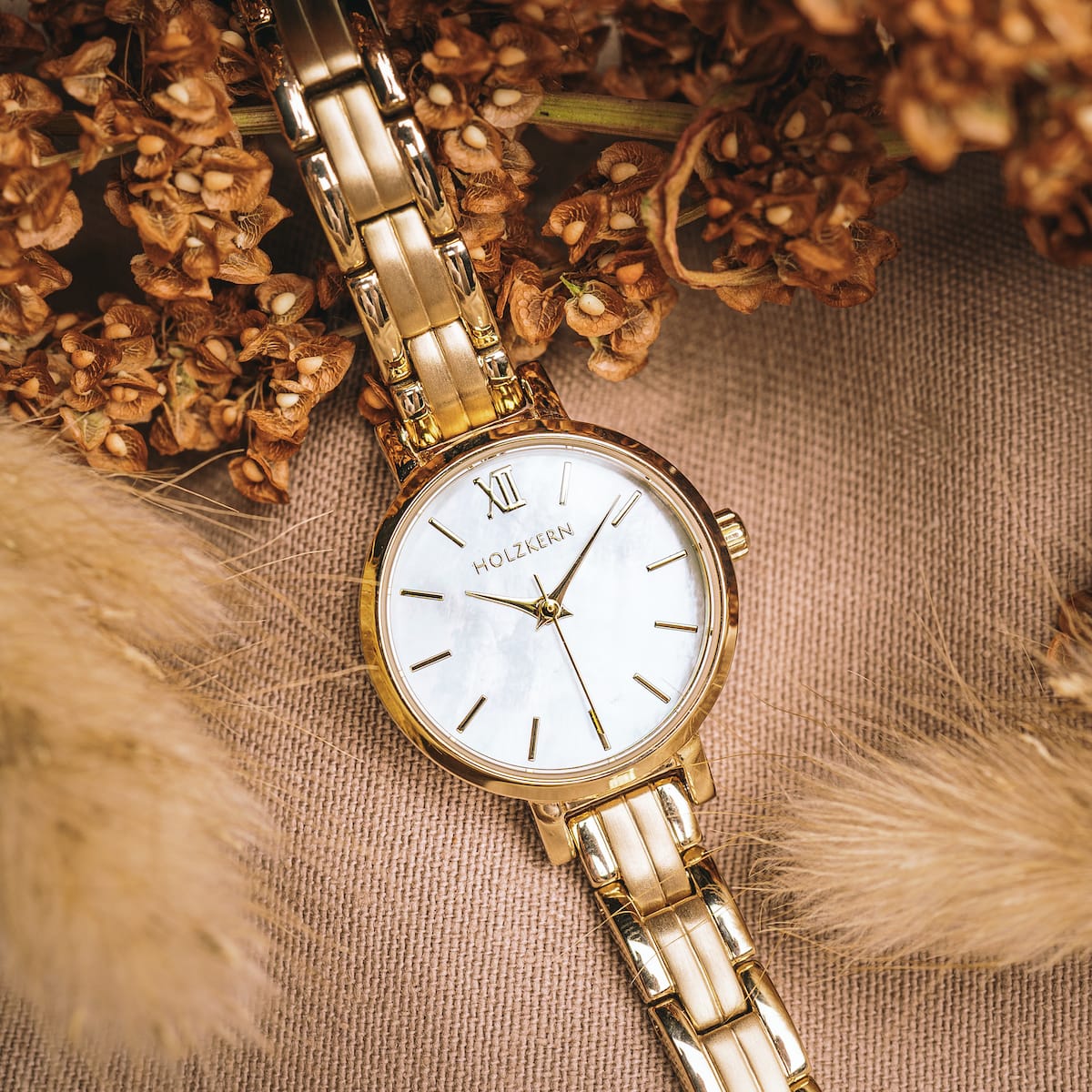 "Hanwi" watch featuring a nacre dial and gold bracelet surrounded by dried flowers.