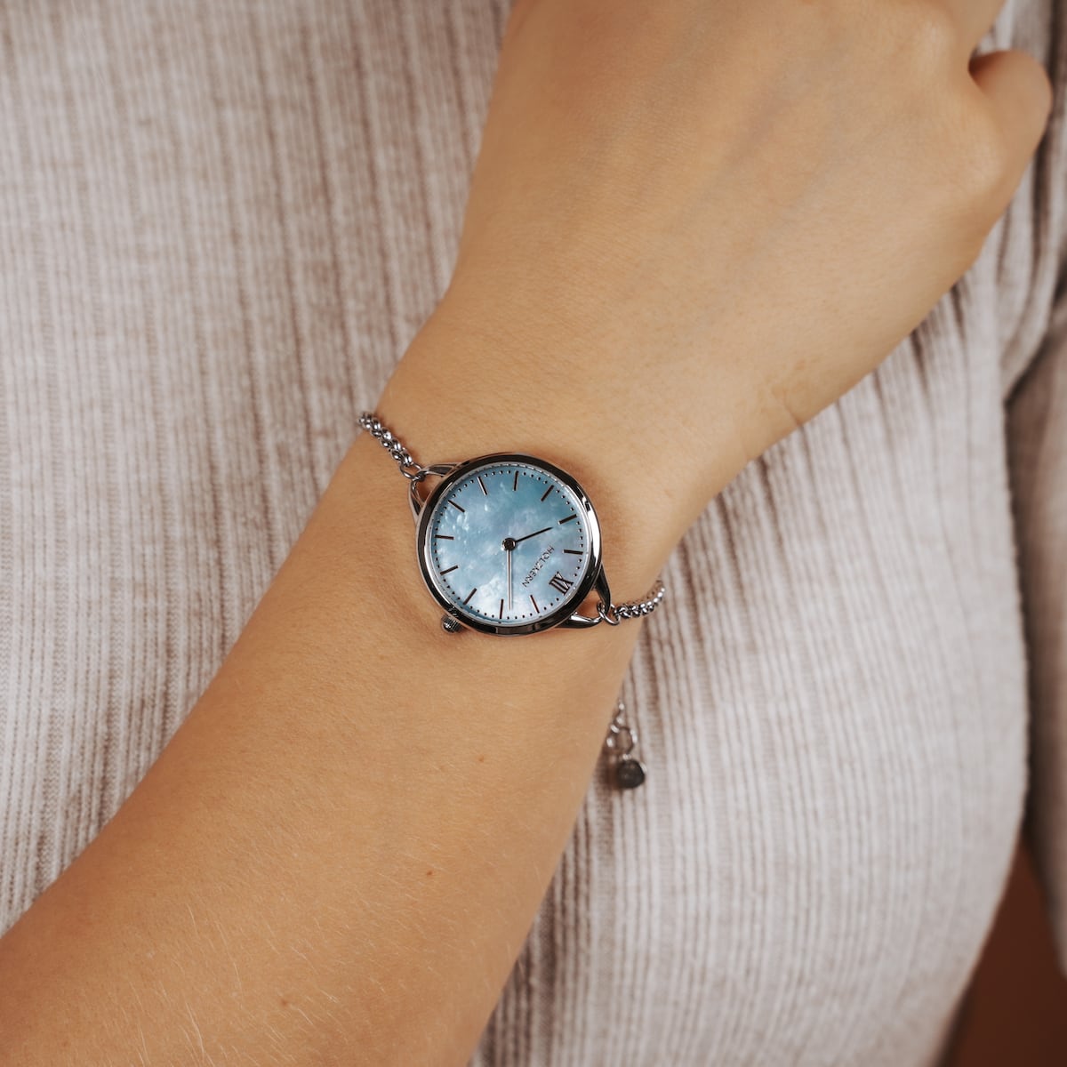 "Brighter" watch, featuring a nacre dial and silver accents, reflecting elegant style on a wrist.