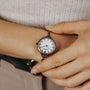 "Touching" watch featuring a nacre face and antique copper finish, worn on wrist for a classic look.
