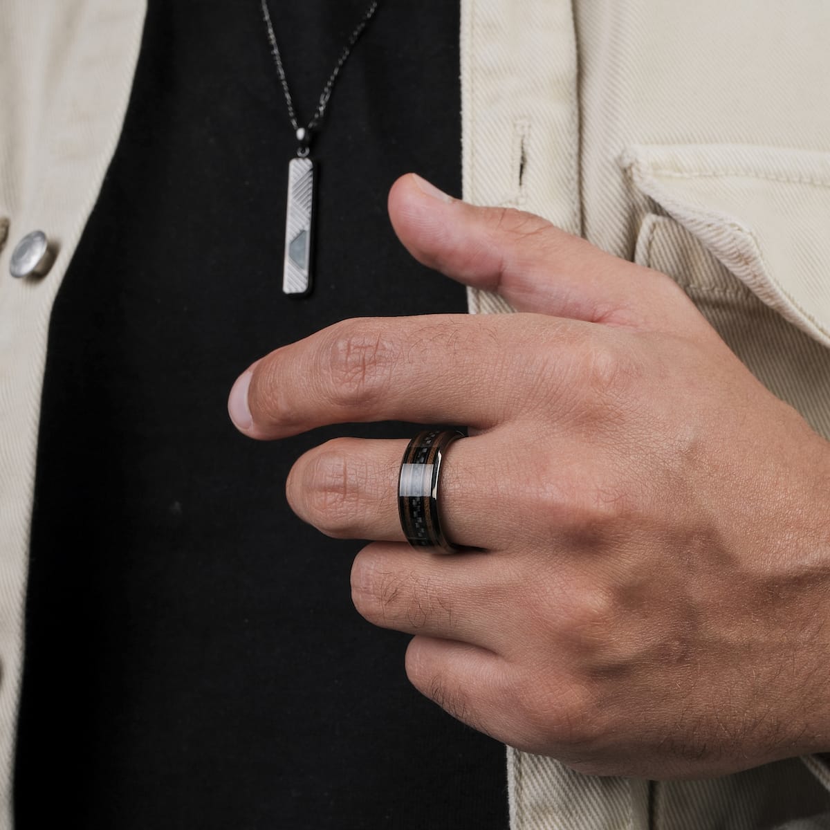 "Cartesian Ring", a stylish ring with walnut and carbon accents, worn on a hand against a casual outfit.
