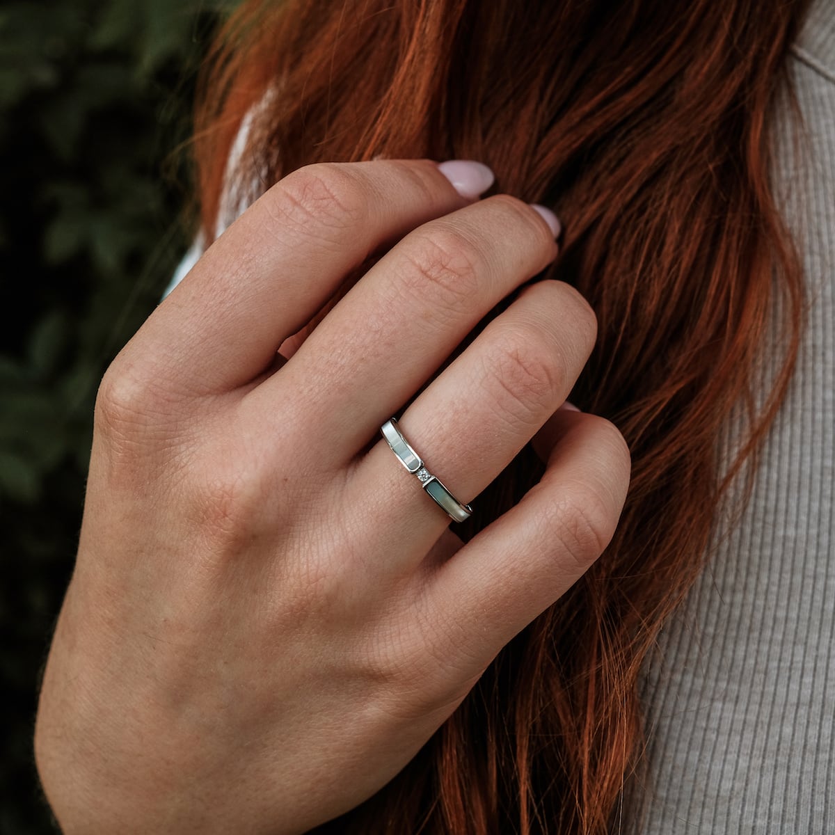 "Campania Ring", elegant silver ring with nacre inlay, worn on a hand against a natural backdrop.