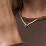 "Awakening Necklace", a stylish necklace featuring marble and gold, worn elegantly around the neck.