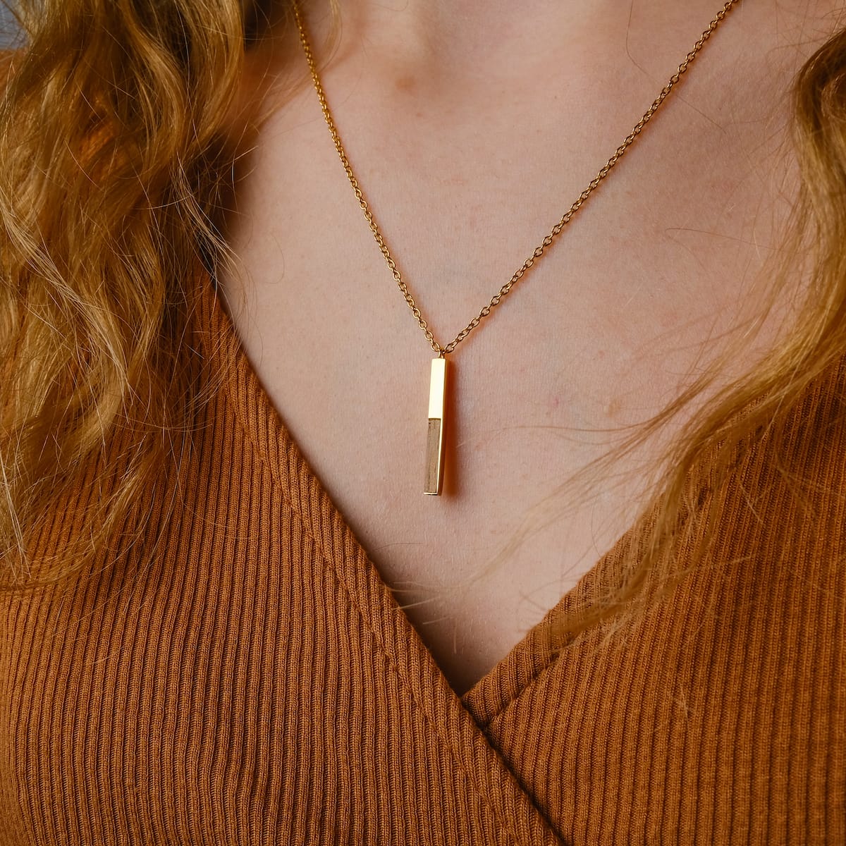 "Campania Necklace": Elegant gold and wood pendant necklace with a minimalist design.