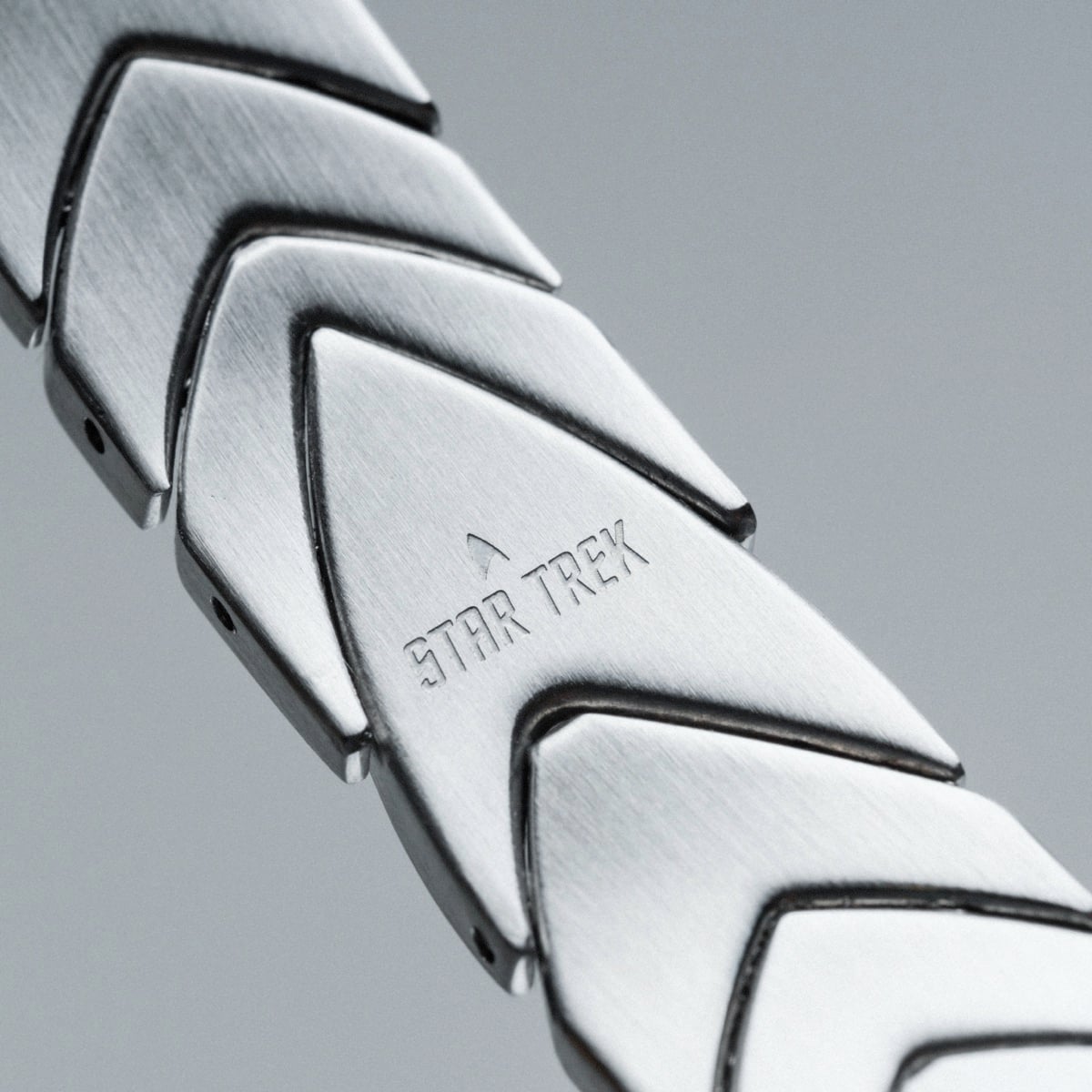 "Command", a sleek silver bracelet with a polished jade accent, featuring a futuristic, modern design.