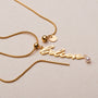 "Believe-Charm" necklace in gold with pearl accent, featuring a stylish script charm design.