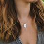 "Aquarell Necklace", a stylish necklace with white nacre and silver, worn on a person.