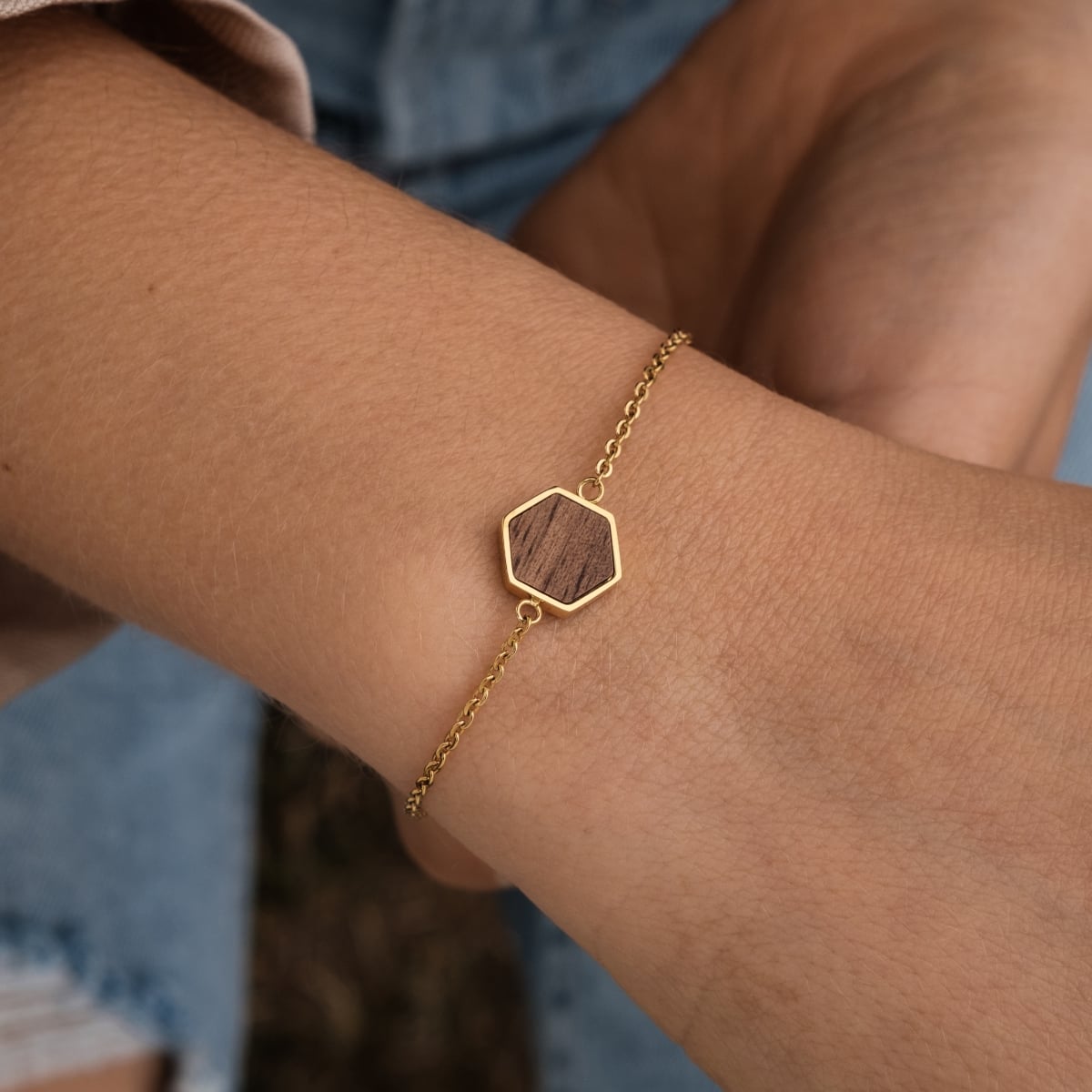 "Facade Bracelet" bracelet, featuring walnut and gold design with a geometric hexagon pendant on a delicate chain.