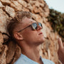 "The Logician" sunglasses, featuring a sleek zebrawood and dark grey design, worn stylishly outdoors.