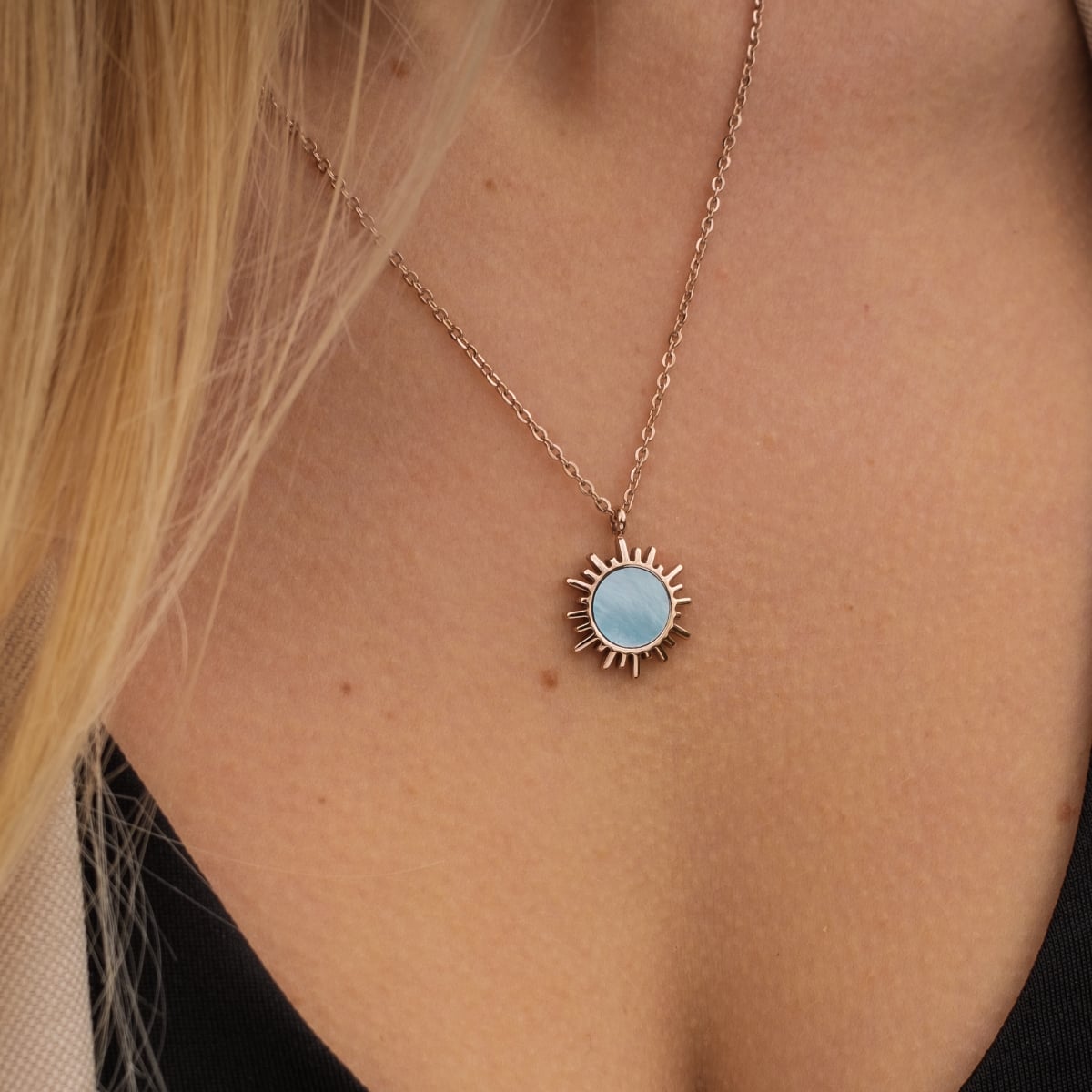 "Shade Necklace" necklace with blue nacre and rose gold, featuring a sunburst pendant on a delicate chain.