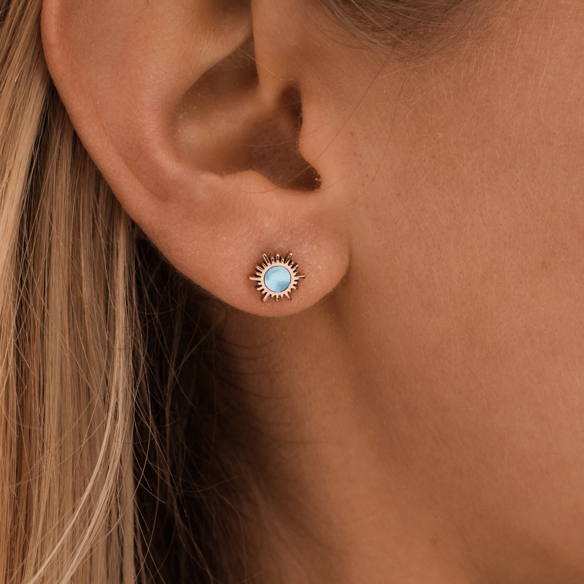 "Shade Earrings" stud earrings with a sunburst design, featuring blue nacre and rose gold accents.