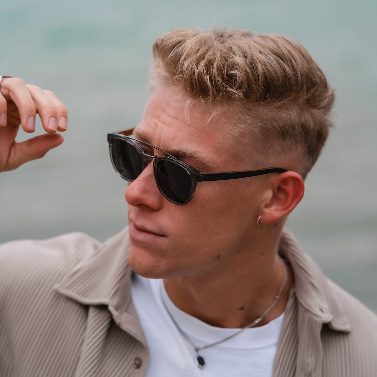"The Trustworthy" sunglasses featuring a sleek design in dark shades, worn by a person outdoors with a calm expression.