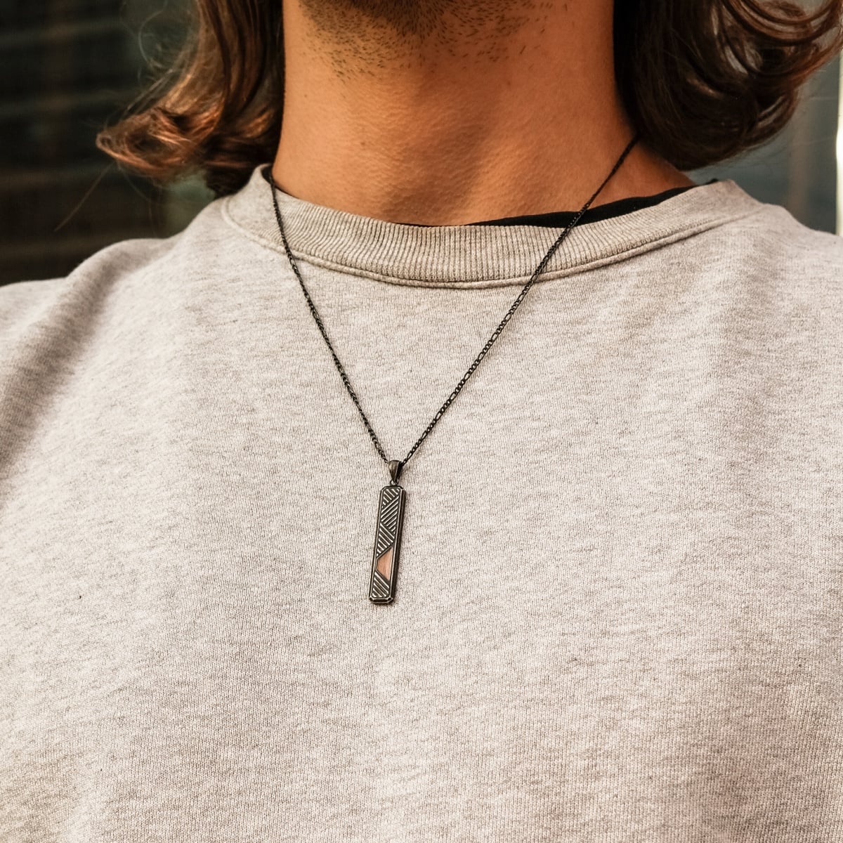 "Derivatives Necklace", a necklace with a walnut and antique silver aesthetic, worn over a casual outfit.