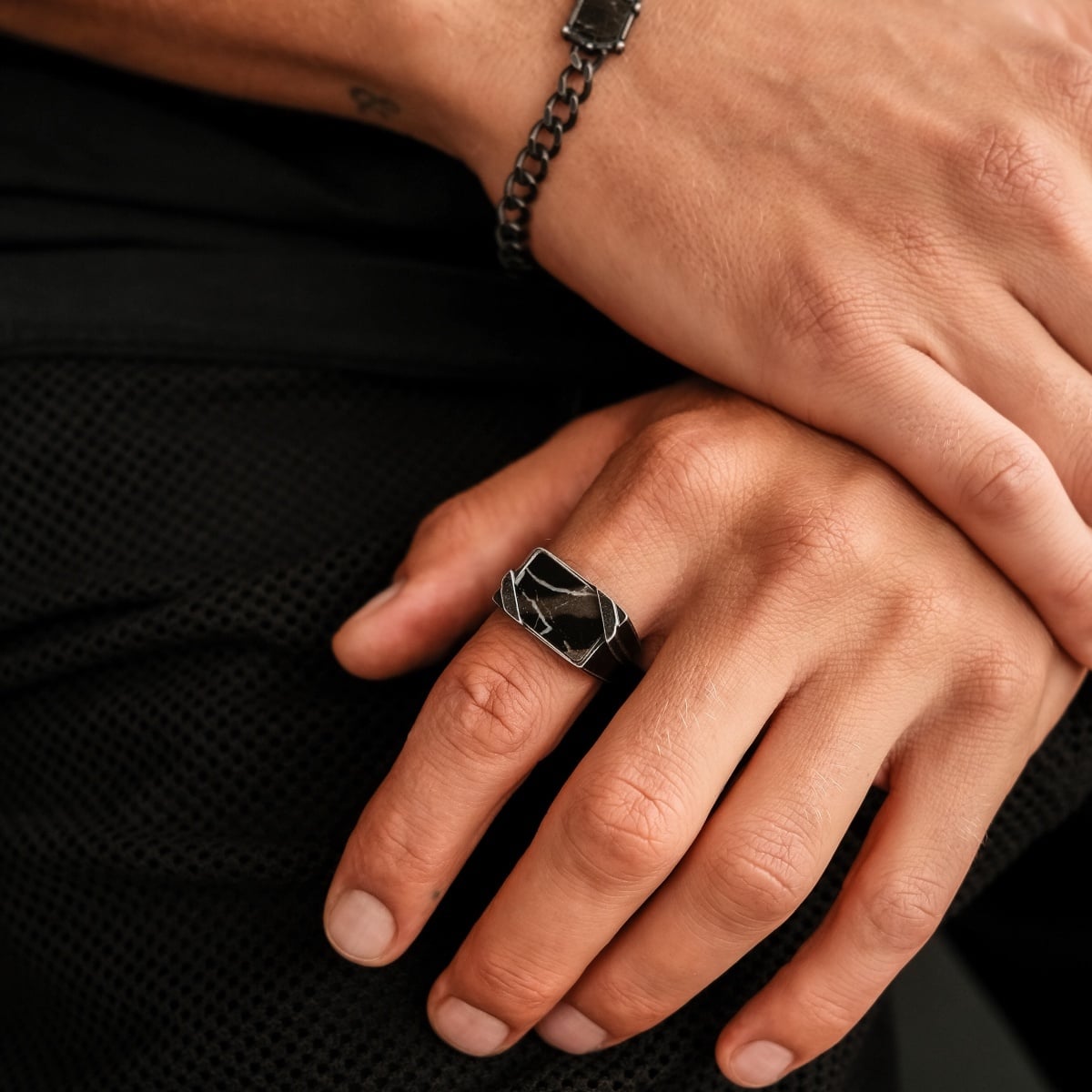 "Binomial Ring" ring featuring a marble and antique silver design, worn on a person's hand for a stylish, contemporary look.