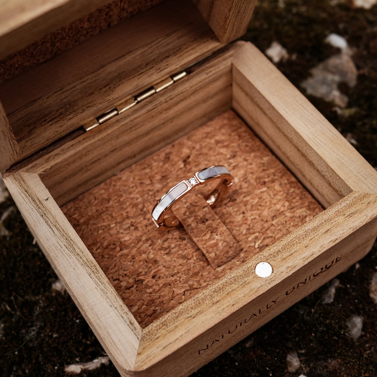 "Campania Ring", a rose gold ring featuring nacre, displayed in a wooden box with a natural, elegant style.