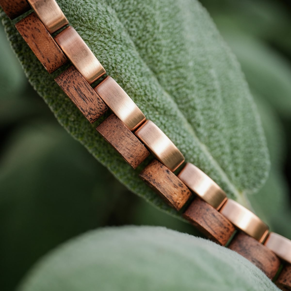 "Duet", bracelet, features a sleek walnut and rose gold design against a natural background.