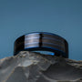 "Cartesian Ring", a stylish ring with a maple wood inlay and blue accents, showcased on a stone surface.