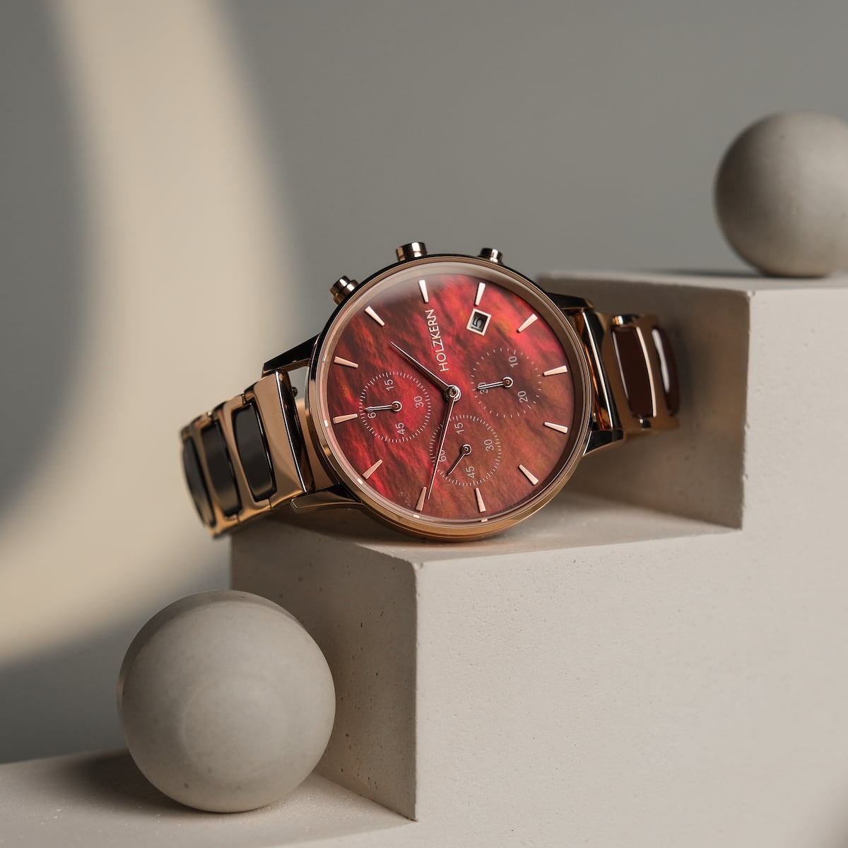 "Cheery", a stylish watch featuring a red nacre dial and ceramic accents, elegantly displayed on a geometric surface.