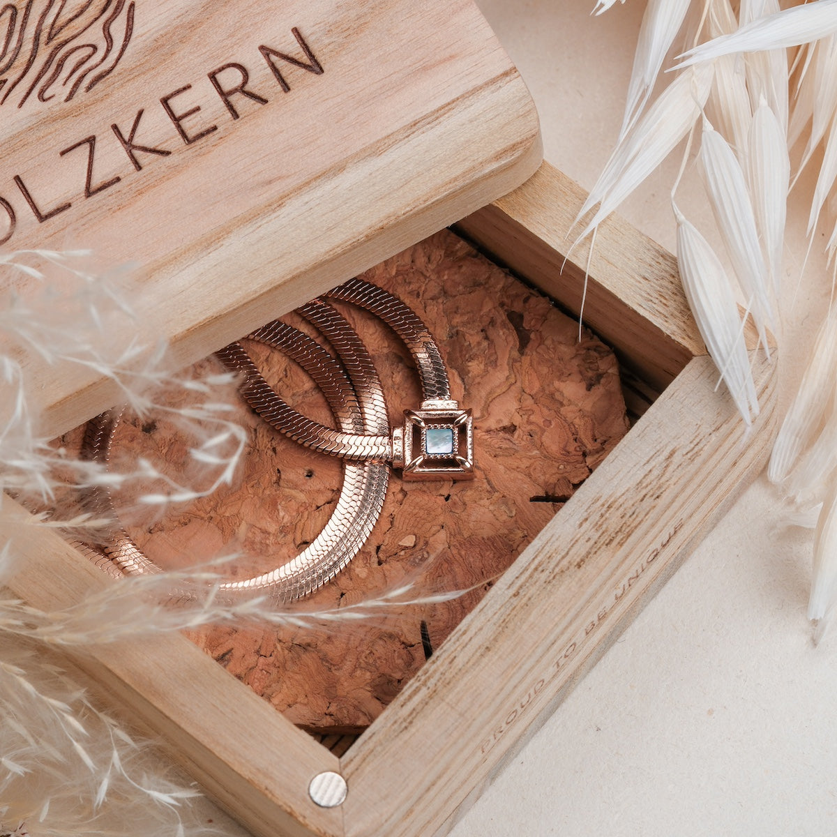 "Awakening Necklace" necklace, featuring nacre and rose gold, elegantly displayed in a rustic wooden box.
