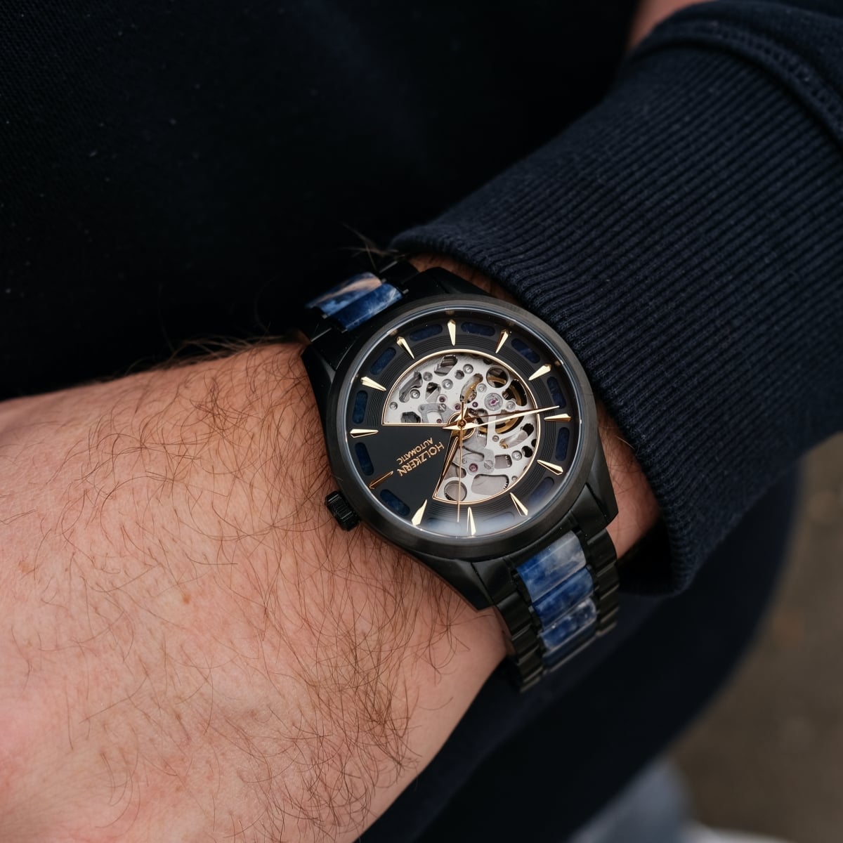 "Vredefort" marble and black watch showcasing a stylish, open-face design with gold accents.