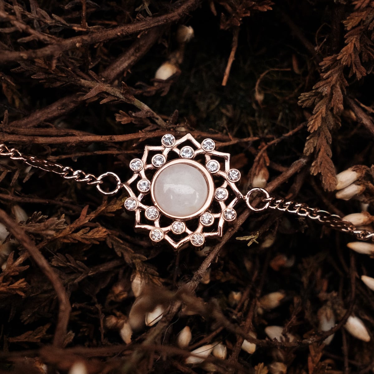 "Composition Gem Bracelet" — Elegant bracelet featuring a moonstone centerpiece with rose gold accents, styled against a natural backdrop.
