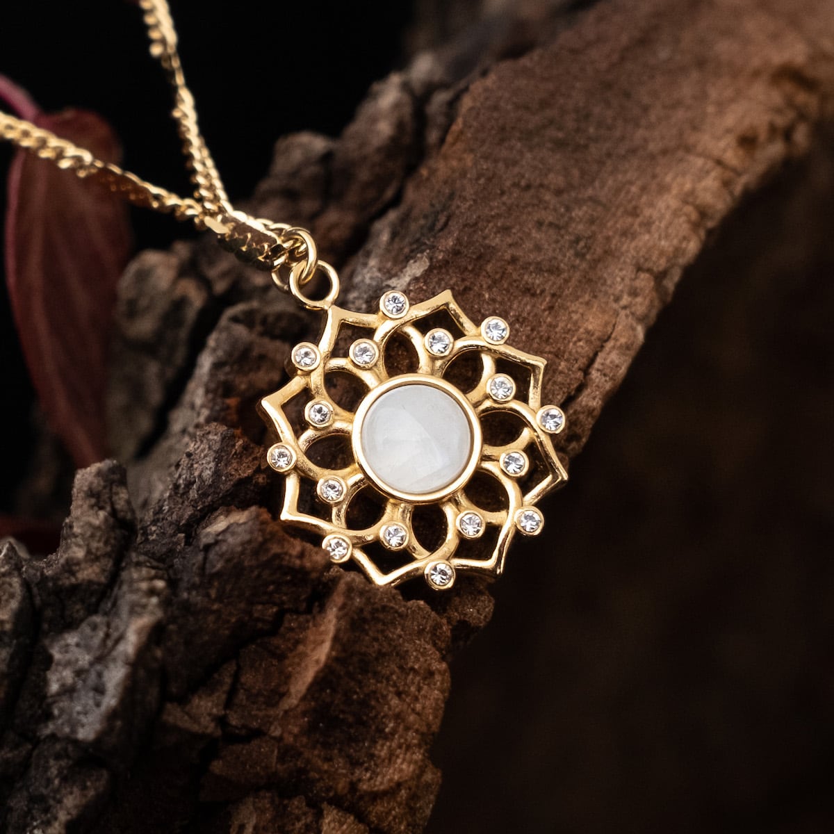 "Composition Gem Necklace" necklace with a gold floral frame, moonstone center, and crystal accents.