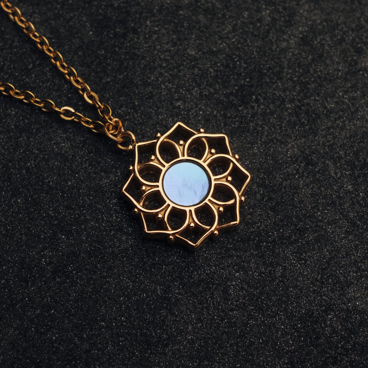 "Composition Necklace": Elegant gold necklace with a blue nacre centerpiece, featuring intricate design details.