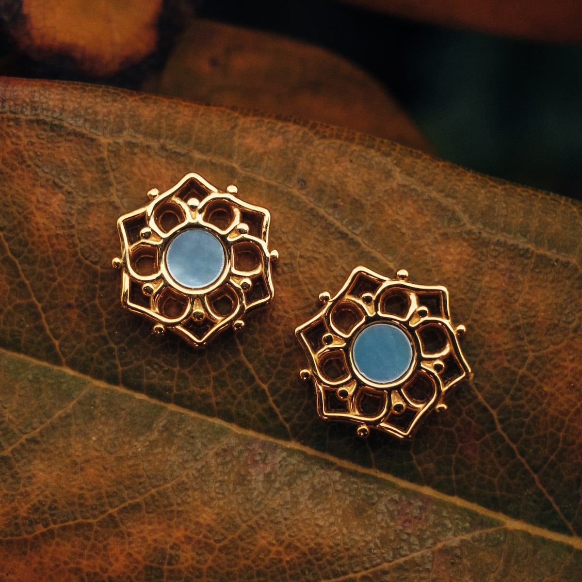 "Composition Earrings": Elegant earrings featuring blue nacre and gold in an intricate floral design.