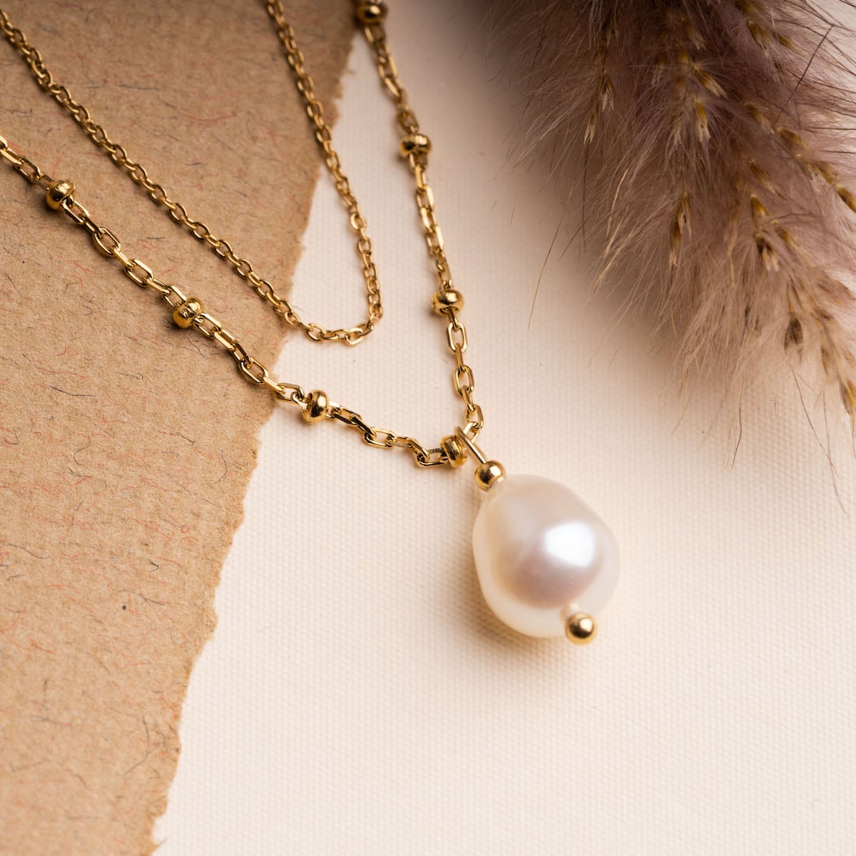 Panoramic Necklace, a gold necklace with a white pearl pendant, showcasing an elegant and timeless style.