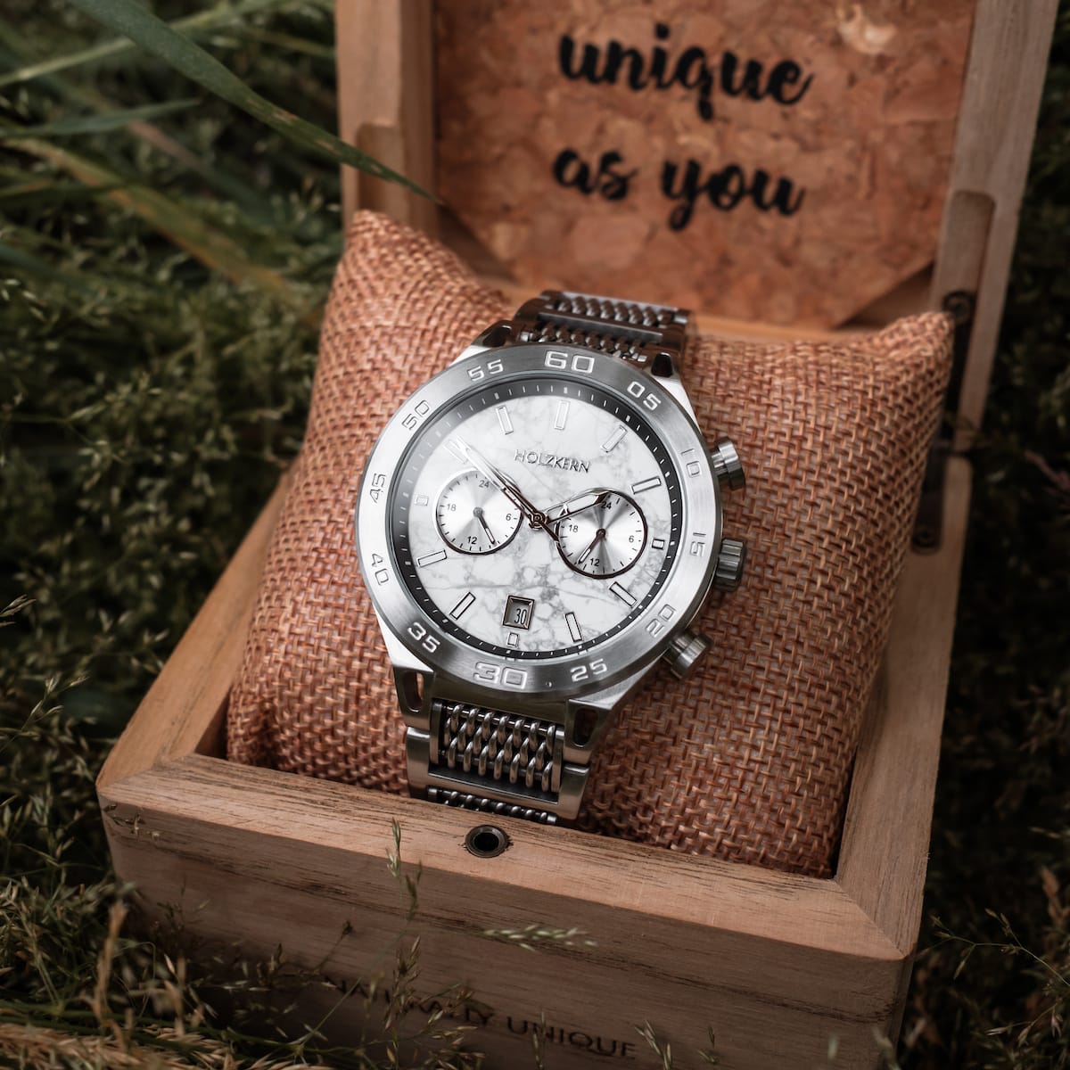 "Elqui" wristwatch with marble face and silver detailing, displayed on a textured pillow in a wooden box.