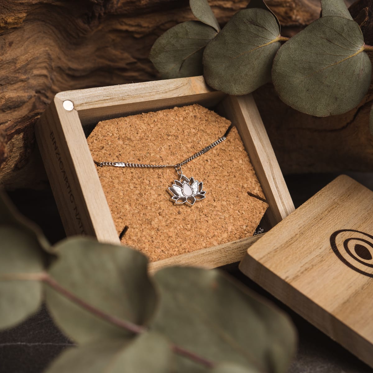 "Balance Necklace", a silver necklace with a marble accent, nestled in a wooden box for an elegant presentation.
