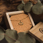 "Balance Necklace" necklace featuring an olive and gold design in a rustic box setting.