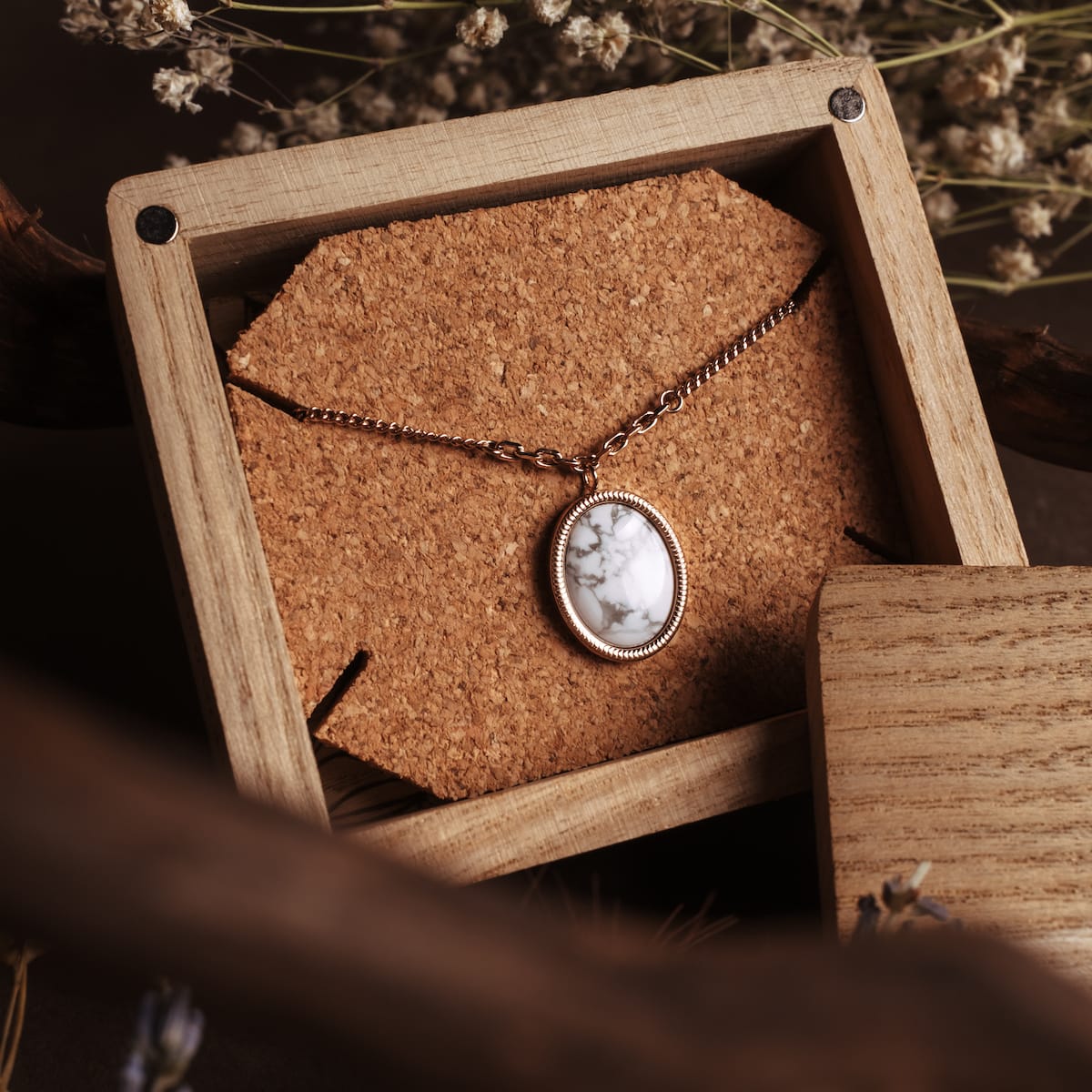 "Mirror Necklace" necklace featuring a turquoise stone set in rose gold, styled in a rustic wooden box.