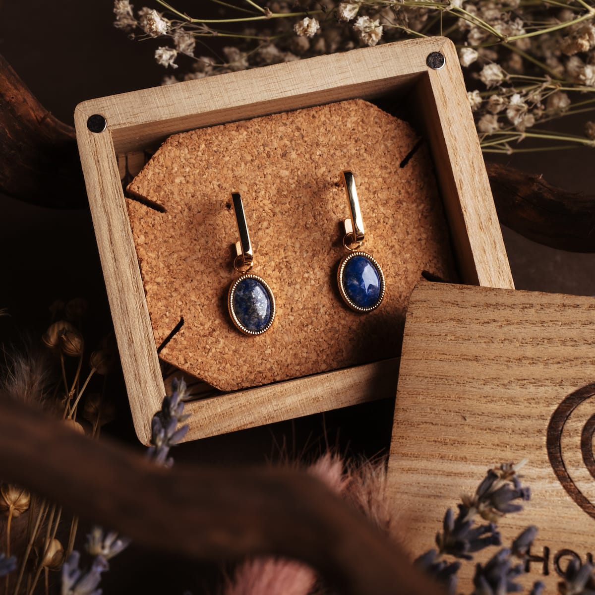 Mirror earrings: Elegant earrings featuring lapis lazuli and gold accents, presented in a rustic wooden box.