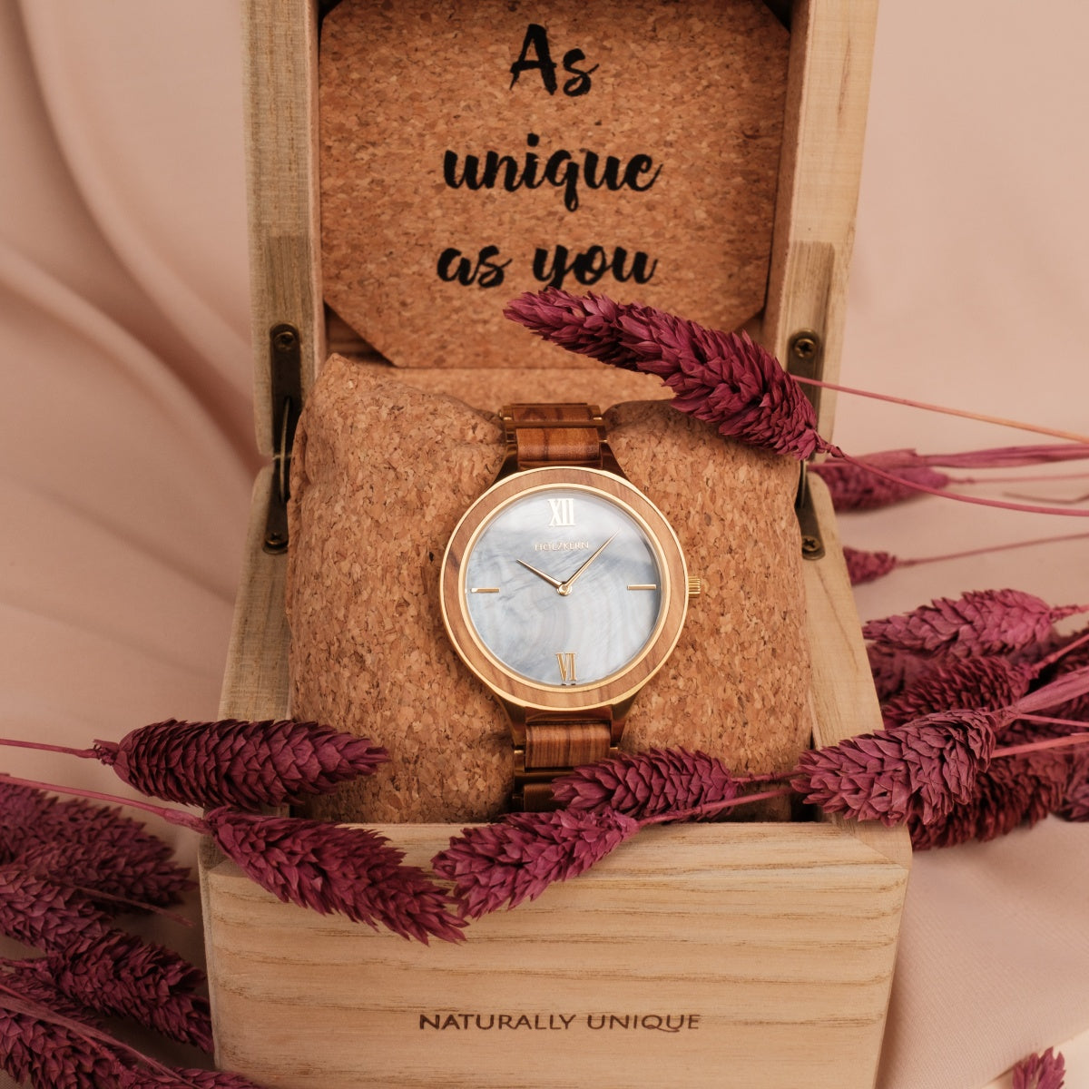 "Capri" watch with a wooden band and nacre dial, elegantly displayed in a rustic box with floral accents.